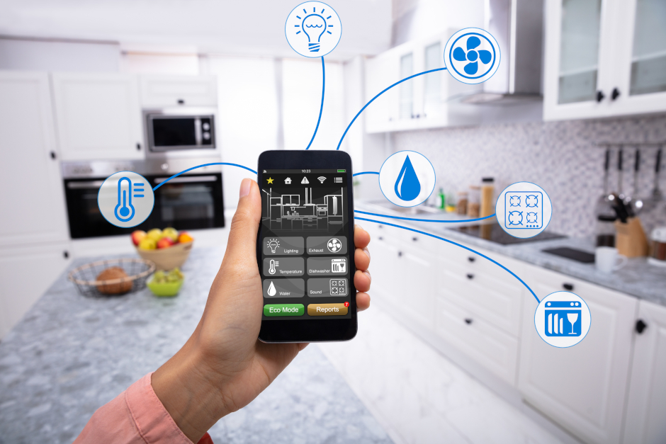 Image of person's hand holding a smartphone in a kitchen.