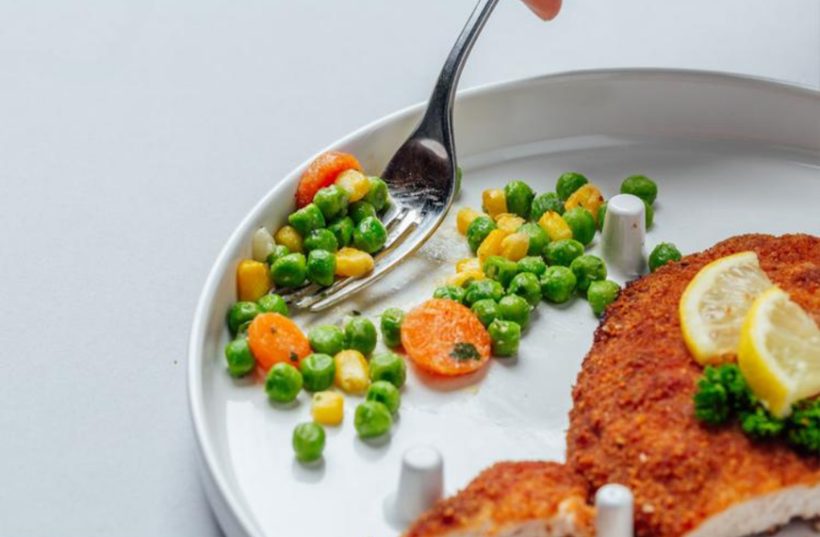 An image of the one hand plate, with food between the cylinder pegs that hold food in place.