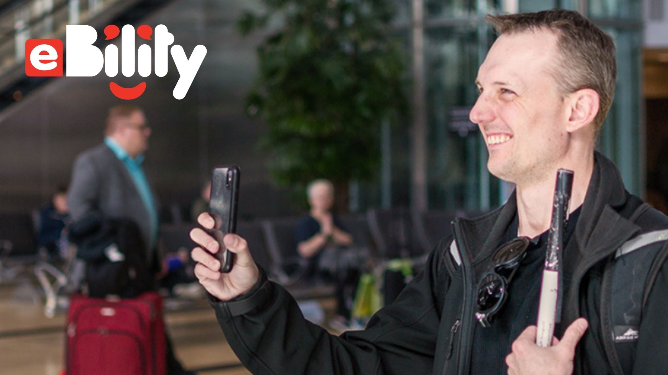 A blind man with can holds up his smart phone for an aira agent to assist him with the obstacles.